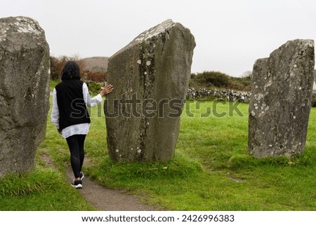 Unrecognizable woman visiting a beautiful archaeological site belonging to the Dromberg megalithic circle in County Cork in Ireland on her road trip through this country