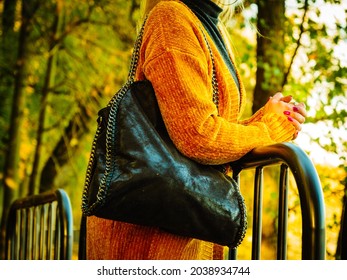 Unrecognizable woman wearing long orange warm cardigan sweater. Autumnal fashion, autumn season styled outfits. Female having a walk in park