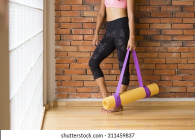 Unrecognizable Woman In A Yoga Studio Indoors, Against A Brick Wall With A Mat.