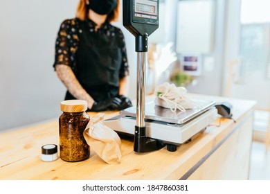 Unrecognizable Woman In Zero Waste Shop Behind Counter. Weighing Dry Goods In Plastic Free Grocery Store. Girl With Weigh Cotton Reusable Bag With Nuts On Scales. Eco Shopping At Local Business