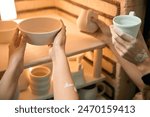 Unrecognizable women potters placing clay ceramics mugs kiln