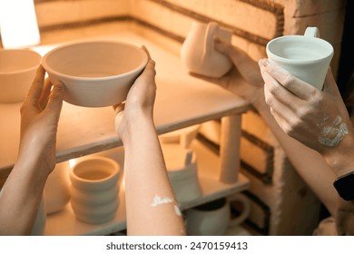 Unrecognizable women potters placing clay ceramics mugs kiln - Powered by Shutterstock