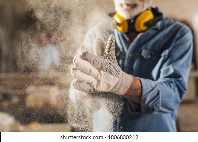 Unrecognizable worker is rubbing his work gloves to clean them from sawdust - Powered by Shutterstock