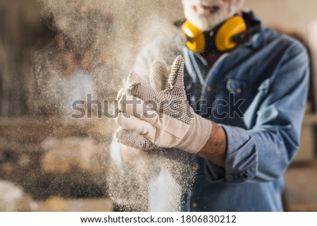 Unrecognizable worker is rubbing his work gloves to clean them from sawdust