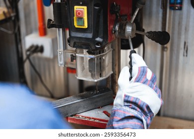 Unrecognizable worker using drill press in workshop