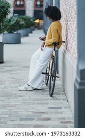 Unrecognizable Young black african american woman on a cool yellow fixie bike in front of pink brick wall