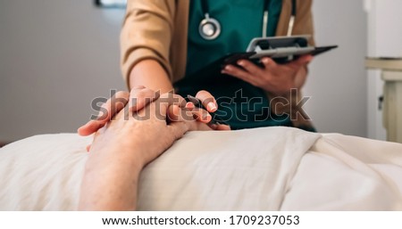 Unrecognizable young female doctor comforting unrecognizable older female patient