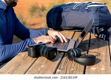 Unrecognizable young guy with a beard working with his laptop on a wooden table in nature - digital nomad concept - Powered by Shutterstock