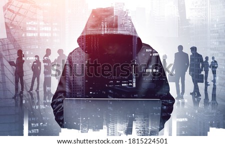 Unrecognizable young hacker in hoodie using laptop in blurry city. Business people. Concept of cybersecurity. Toned image double expsoure