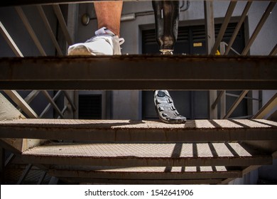 Unrecognizable young man and amputee athlete, testing his new prosthesis by climbing stairs - Powered by Shutterstock