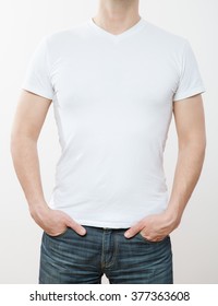 Unrecognizable young man hiding his hands in pockets, white background