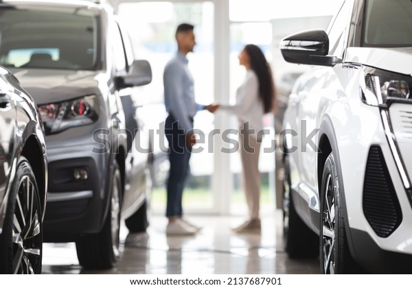 Unrecognizable young\
middle eastern man and woman shaking hands at newest auto showroom,\
blurred background. Customer buying brand new luxury car at\
automobile dealership\
salon