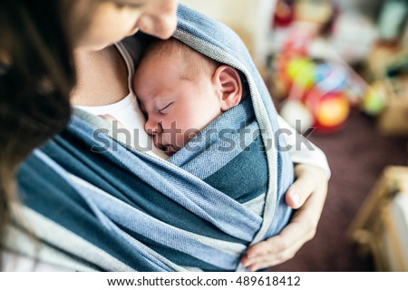 Unrecognizable young mother with her son in sling