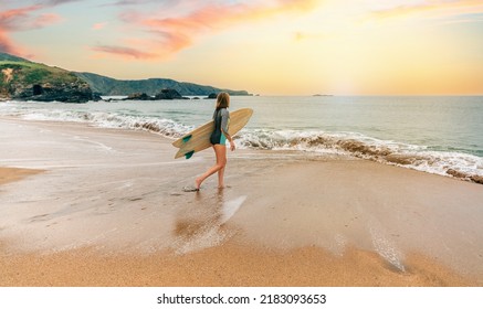 Unrecognizable young surfer woman with wetsuit and surfboard entering the sea
