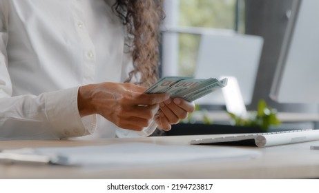 Unrecognizable young woman accountant counts cash at workplace female office worker bank cashier calculates salary with paper dollar bills monthly calculation finance budget savings currency