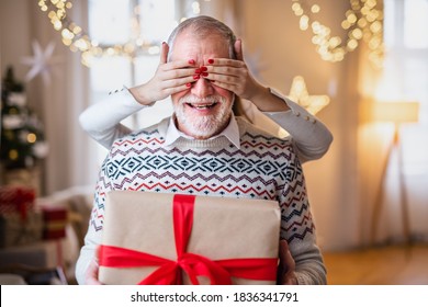 Unrecognizable young woman giving present to senior grandfather indoors at home at Christmas. - Powered by Shutterstock