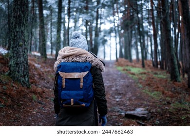 Unrecognizable young woman green coat hat, gloves, hiking backpack, exploring snowy Guadarrama trail - Powered by Shutterstock