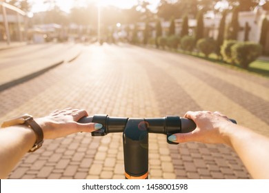 Unrecognizable Young Woman Riding An Electric Scooter In City Park In Summer Outdoor, Point Of View In First Person.