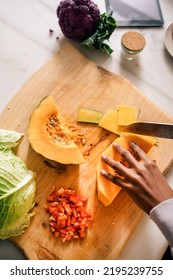 Unrecognized Black Woman Cutting Vegetables In The Kitchen At Home.