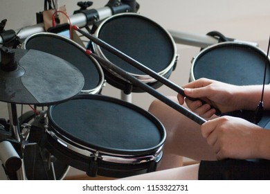 unrecognized boy practicing electronic drums with black drumsticks
