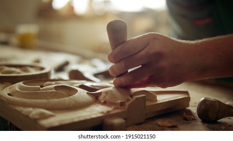 Unrecognized carpenter carving ornament in carpentry workshop. Wood master making decoration on wooden product in studio. Unknown man decorating wood indoors. Handyman using tools. - Powered by Shutterstock