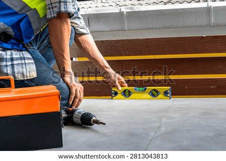 unrecognized construction worker using spirit level tool to check the vertical alignment and accuracy of cement floor during home balcony extension project
