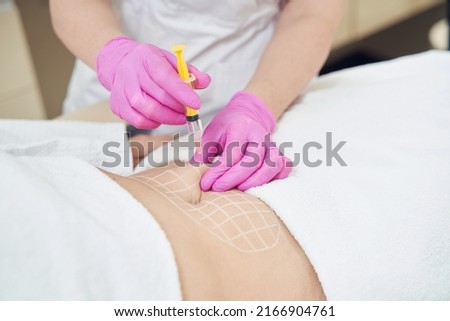 Unrecognized dermatologist is making injection for contouring body in clinic