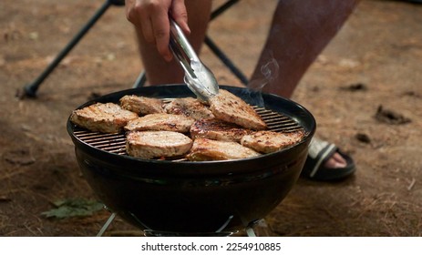 Unrecognized man is cooking BBQ stakes on charcoal grill in the forest. Camping food preparation. Fresh juicy stakes grilling on the barbeque - Shutterstock ID 2254910885