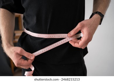 Unrecognized man measuring waist with a tape measure, close up - Powered by Shutterstock