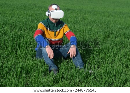 Unrecognized man sitting on green grass in virtual reality glasses, top view. Digital agriculture business. outdoors. High quality photo