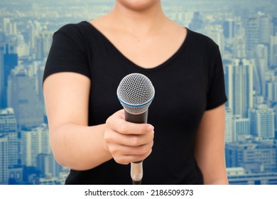 Unrecognized Person Holding Microphone On Cityscape Background.