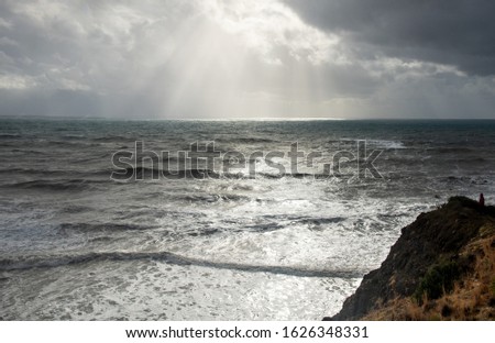 Unrecognized person standing the edge of a cliff end enjoying the dramatic stormy sea. Rock of Aphrodite coastline at Paphos Cyprus