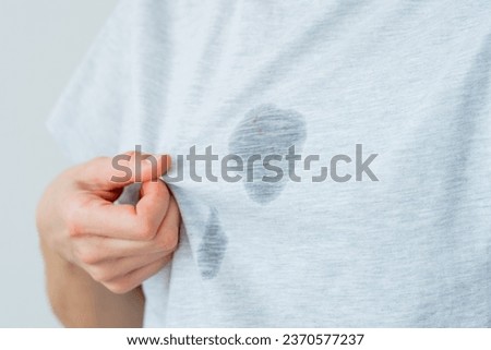 Unrecognized surprised female showing at dirty grease stain on a gray t-shirt. daily life stain concept. High quality photo