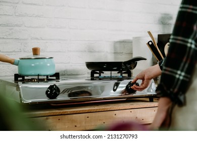 Unrecognized Wife In Home Kitchen Preparing Dinner For Family. Female Hand Turning On And Off Gas Stove Burner Under Frying Pan In Cooking Place. Woman Lighting Up Burning Stove With Fire Warm Pot