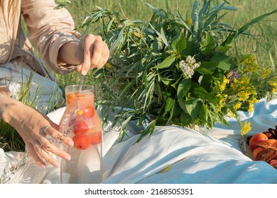 Unrecognized woman making a refreshing drink from strawberries at a picnic. - Shutterstock ID 2168505351