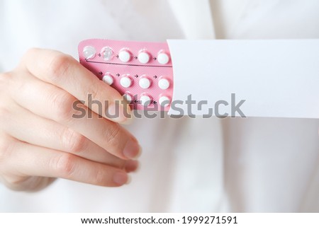 Unrecognized woman in white blouse holding hormonal oral contraceptives in a pink blister. Concept of Hormonal methods of birth control. Estrogen and Progestin hormonal balance. [[stock_photo]] © 