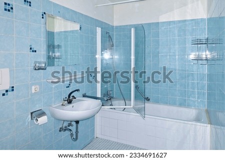 Unrenovated bathroom from the 1970s with the original blue tiles, seventies style. Outdated, neglected and grimy bath in an apartment for rent.