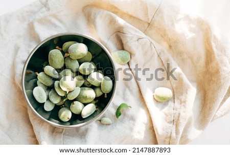 unripe green almonds in a bowl on a light background. copy space. top view. healthy eating concept. 