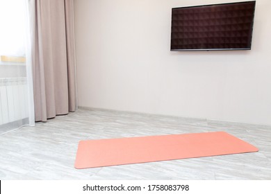 Unrolled Pink Yoga Mat On Floor In Living Room.