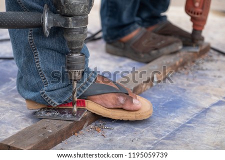unsafe Construction worker Steel drilling with grinder machine cutting metal at building site and unsafe concept Do not put gloves Steel head glasses Dangerous not EPE no Safety in a factory