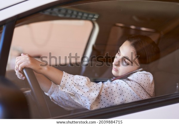 Unsafe driving. Young multiracial woman talking\
on the phone while driving. Distracted Driving. Female driving and\
talking on cellphone