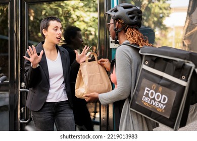 Unsatisfied Client Refuse Taking Late Food Order, Delivery Delay, Courier And Angry Customer. Woman Giving Impulsive Furious Employee Takeaway Meal Near Office Building Outdoors