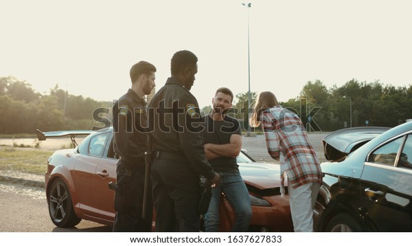 unsatisfied drivers talking with the police\
trying to olve bad situation on road. view of stressful woman and\
man arguing in front of\
policemen.