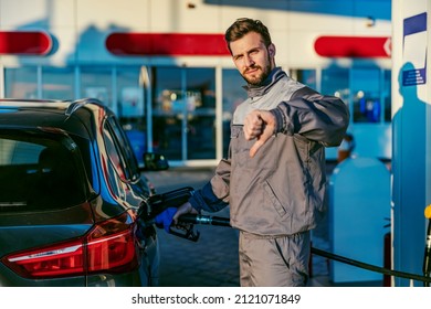 Unsatisfied gas station worker filling up the tank with expensive diesel and giving thumbs down for price increase.