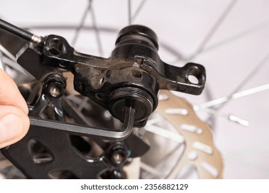 Unscrewing the brake shoe of the bicycle brake caliper with a hexagon. Replacement of brake pads.
