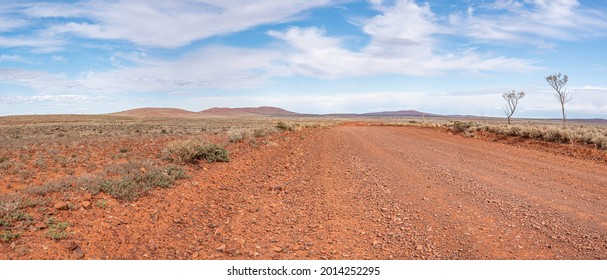 Unsealed Outback road, remote travel. Ultra wide panorama, South Australian landscape. Dirt  road access to remote Outback communities and Stations.