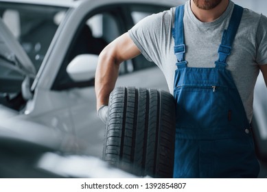 Unshaved man. Mechanic holding a tire at the repair garage. Replacement of winter and summer tires.