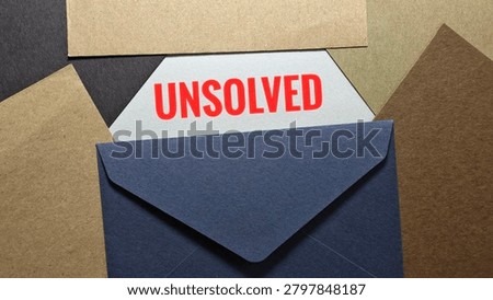 Unsolved Text on White Card Inside Blue Envelope Over Brown Kraft Background, Mystery and Investigation Concept. 