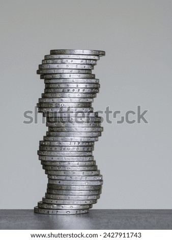 Unstable coins stack of two euro coins on a grey background, future balance concept