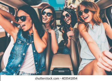 Unstoppable Beauties. Four Beautiful Young Cheerful Women Looking Happy And Playful While Sitting In Car